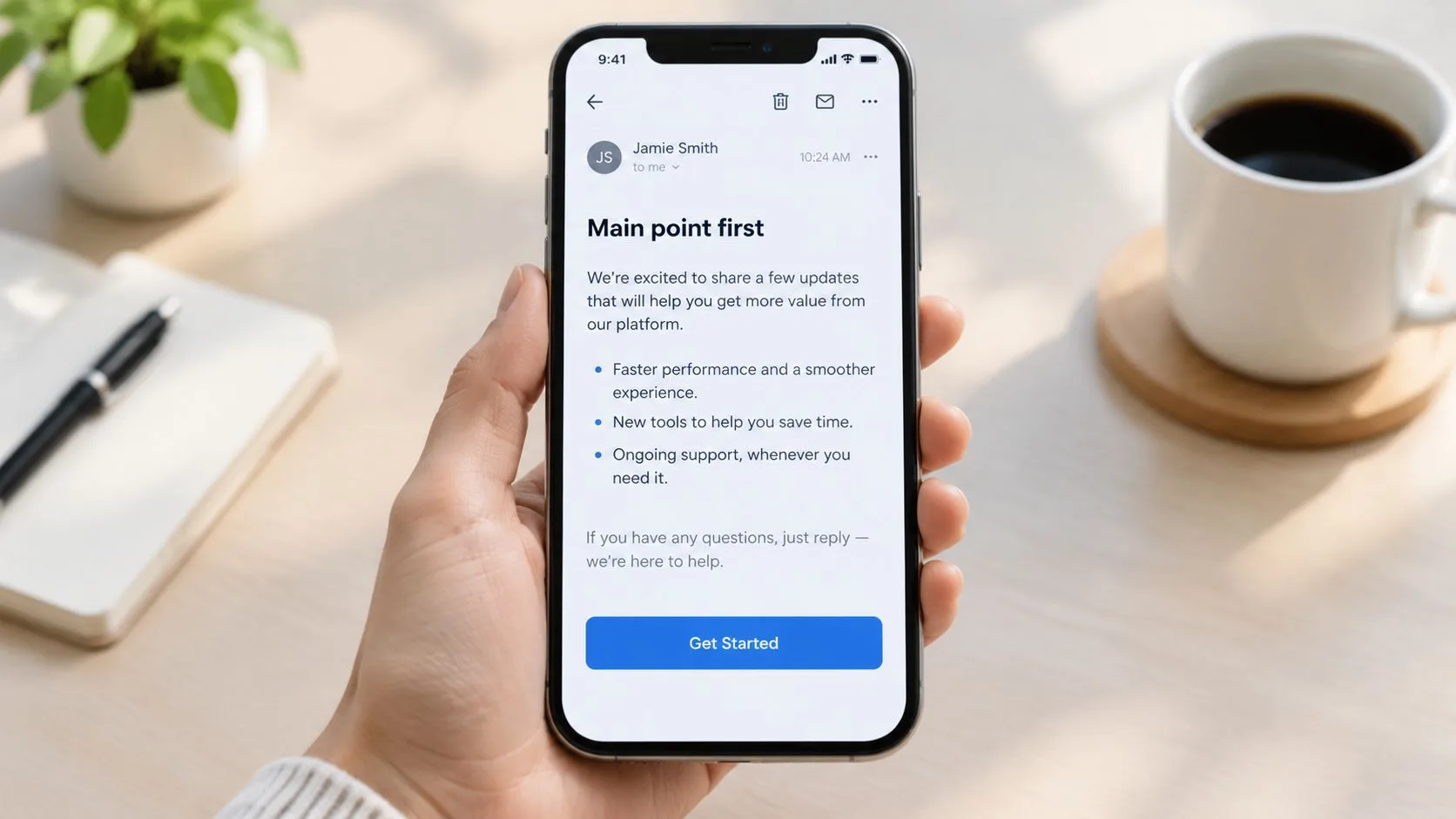 A hand holding a smartphone displaying an email with clear headings, bullet points, and a call-to-action button.