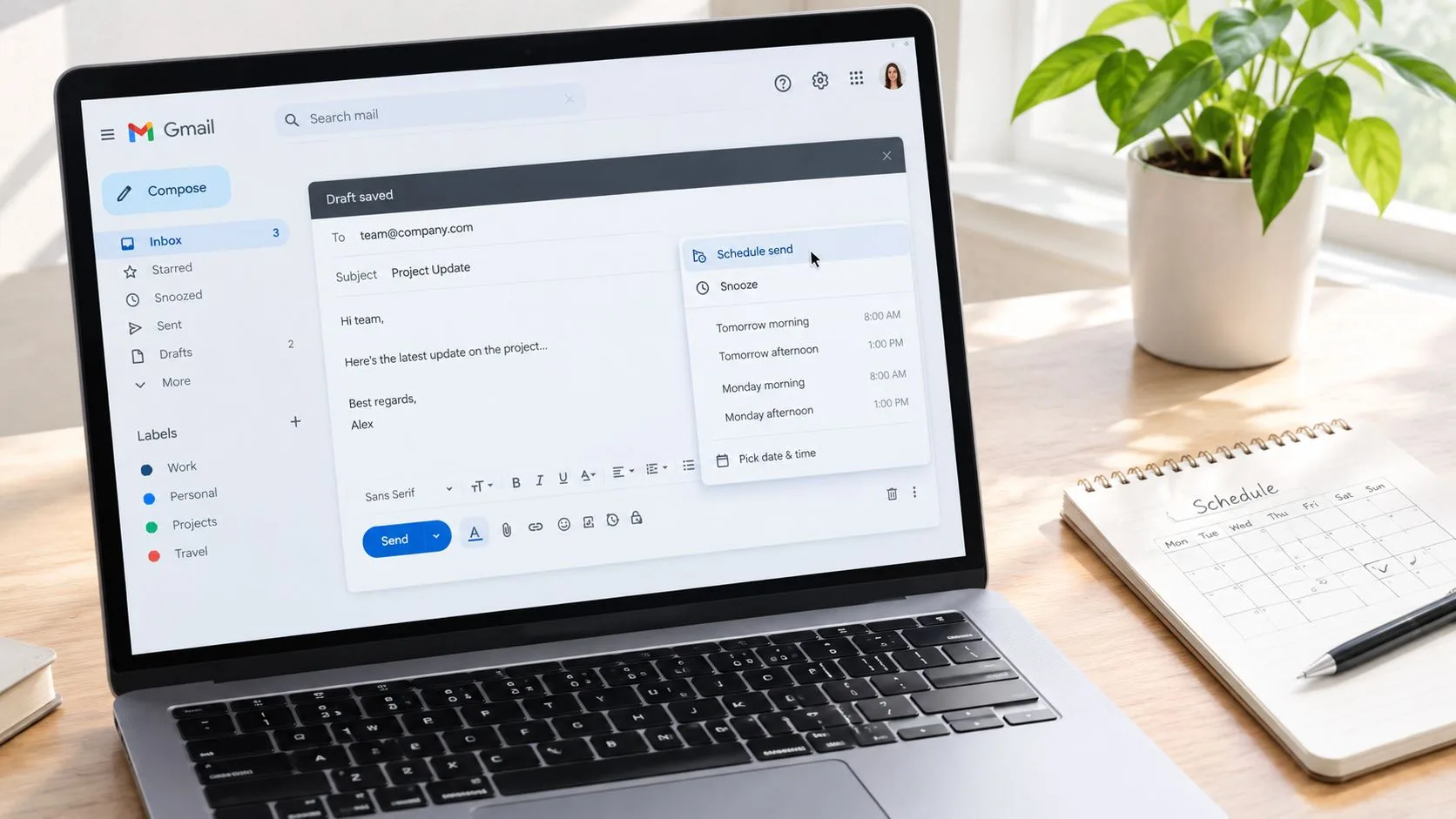 A laptop screen displaying a Gmail draft with a schedule send menu open on a wooden desk.