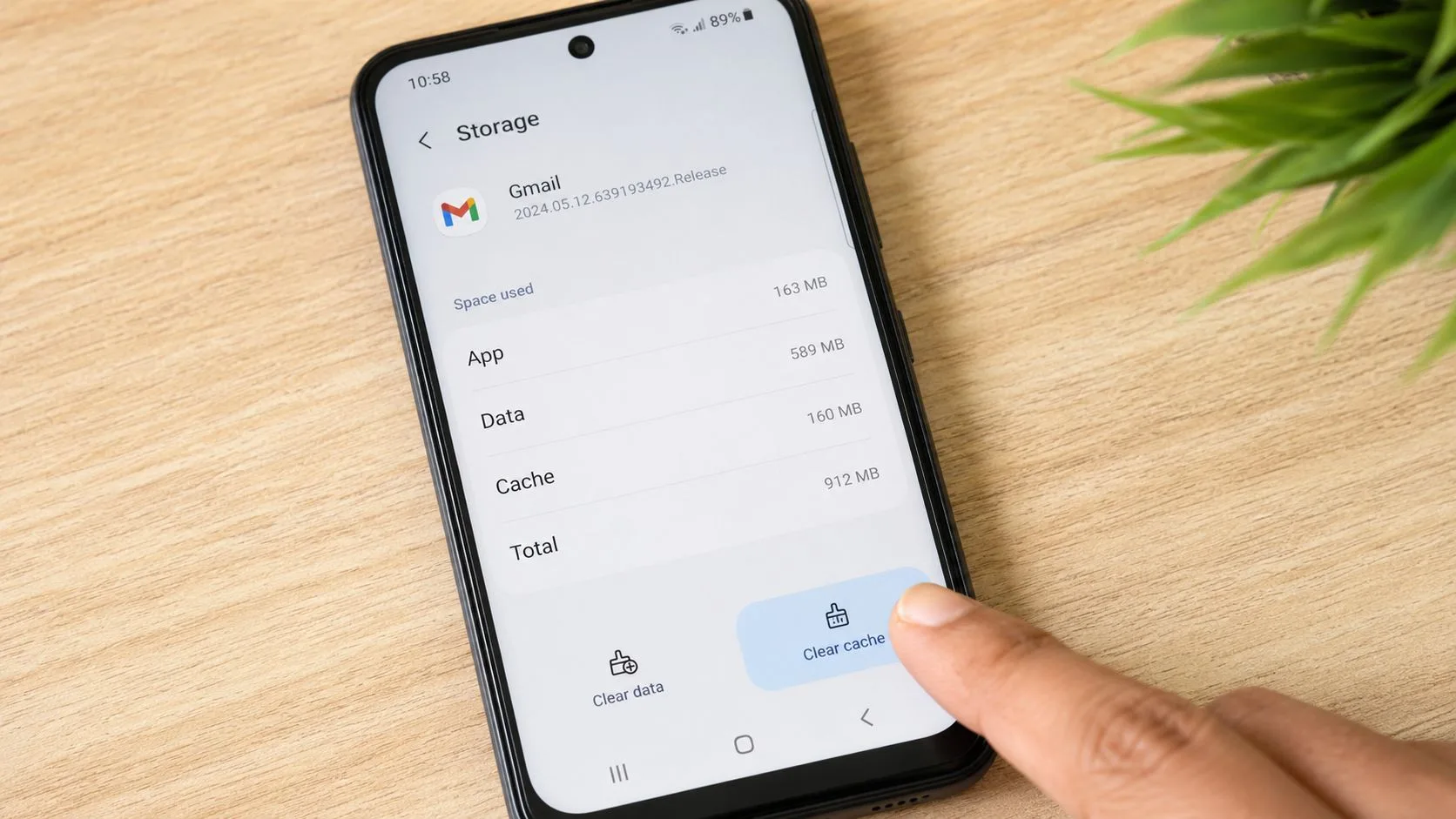 A person pressing the clear cache button for the Gmail app on a modern Android smartphone screen.