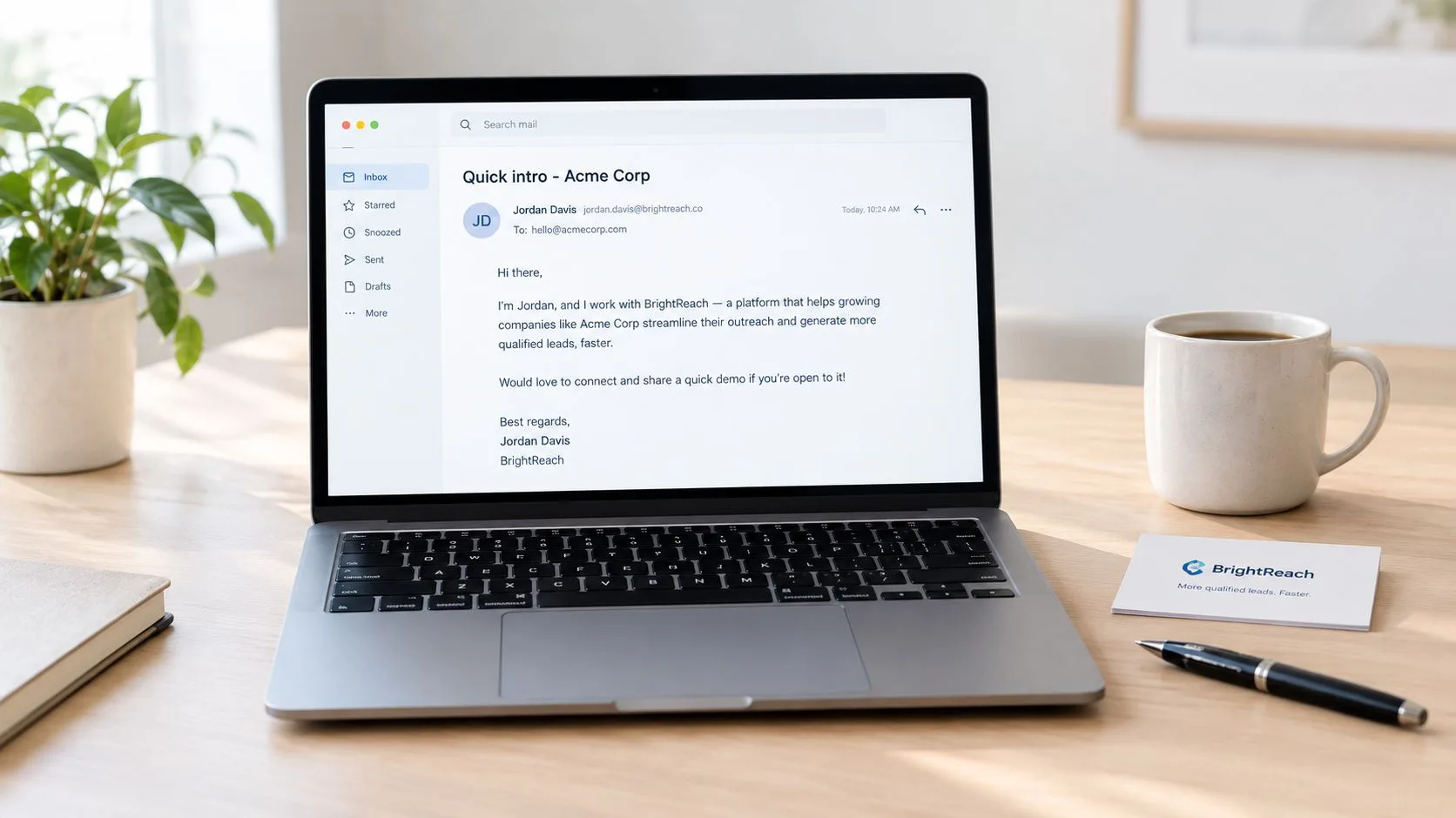 A laptop on a wooden desk displaying a professional business email from BrightReach alongside a coffee mug.